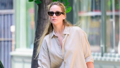Jennifer Lawrence gets into her car wearing a beige shacket and butter yellow pants plus white sneakers